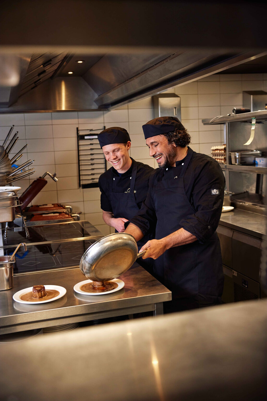 Personeel bij Loetje in actie – lachend, energiek en helemaal in z’n element. Werken in de horeca is leuk, maar werken bij Loetje is leuker. Of je nu biefstukken loopt te knallen in de keuken, gasten blij maakt in de bediening of door wil groeien tot locatiemanager: bij Loetje zit je goed.